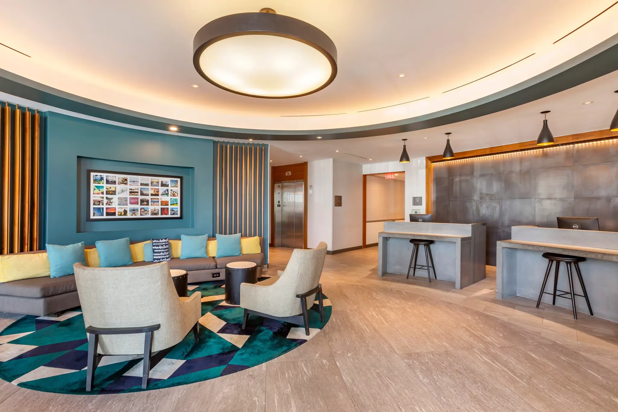 Modern hotel lobby with a circular chandelier, colorful seating area, geometric rug