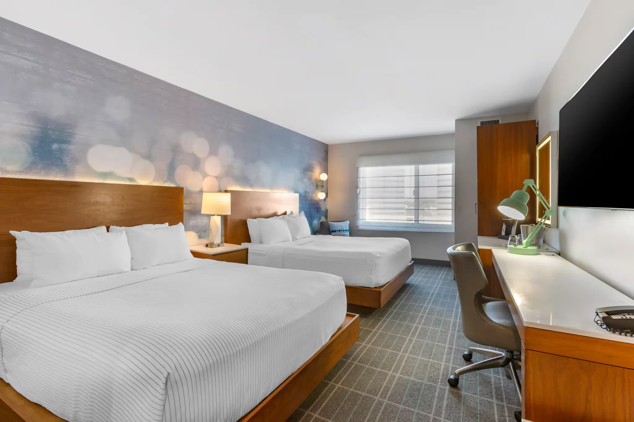 Room with two large beds, white linens, and a soft-focus wall mural