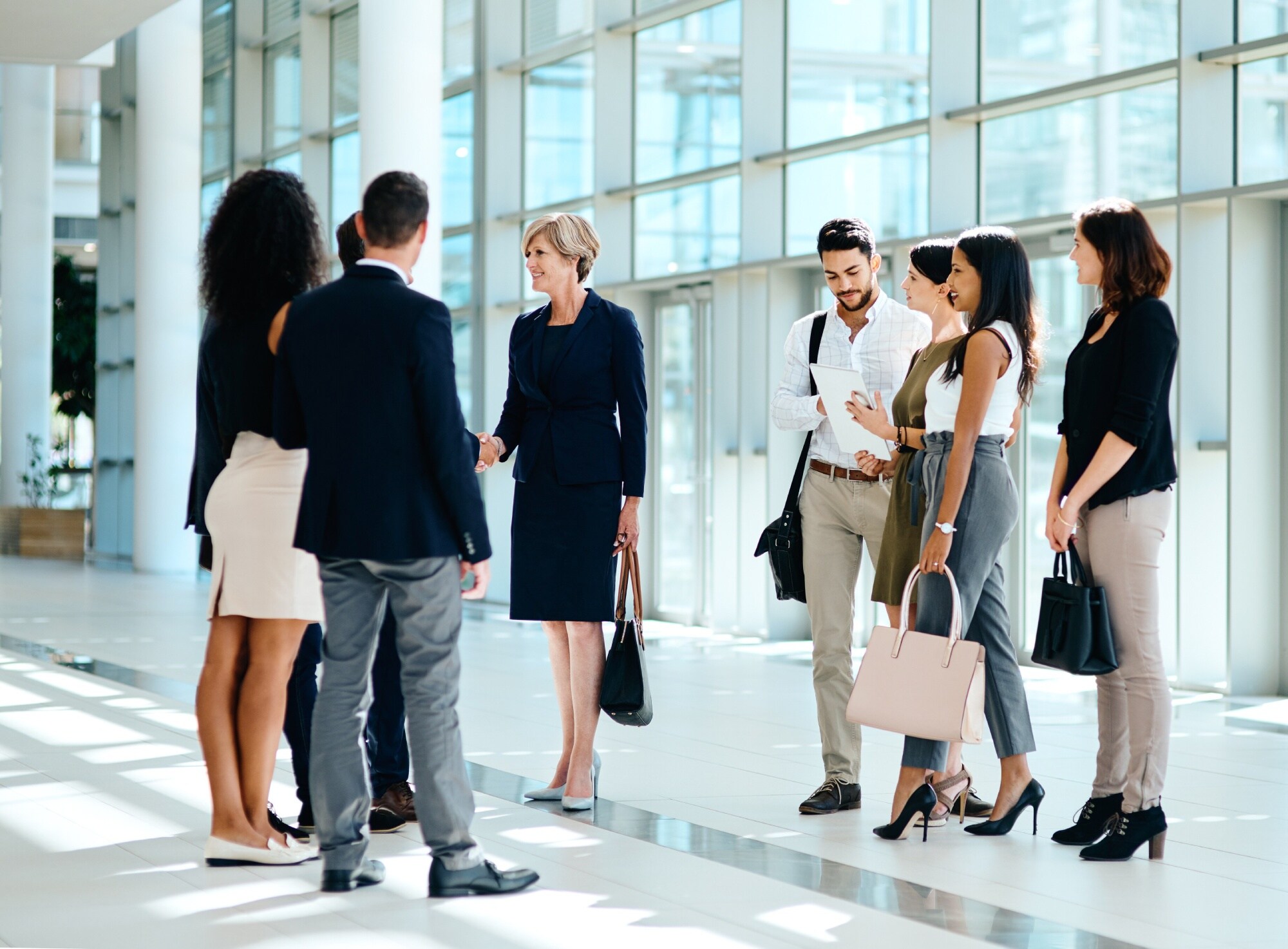 A group of business professionals standing together in a modern office lobby, engaged in conversation
