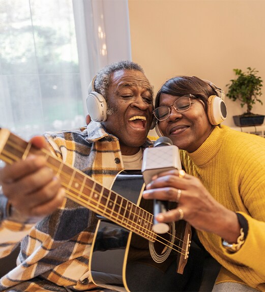 Man and woman with a guitar and microphone enjoying playing music