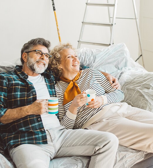 Middle aged couple sitting on their couch looking up at their home improvement HELOC project