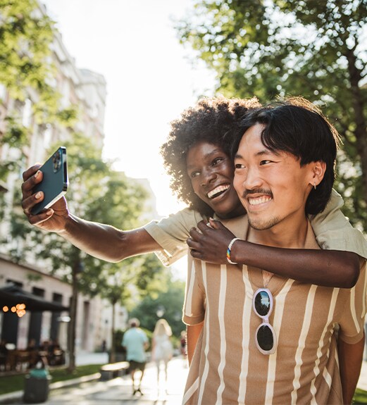 Smiling young couple taking a selfie walking down a sunny street