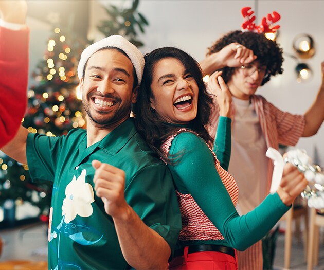 Friends wearing holiday outfits and dancing at a holiday party