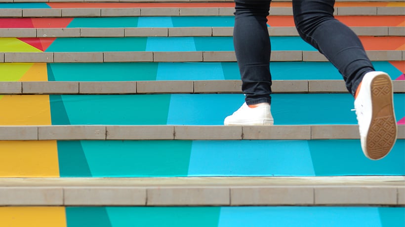 Close up of person's feet climbing up brightly colored stairs