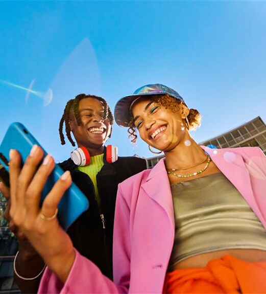 Two friends wearing colorful clothing playing music on their phones