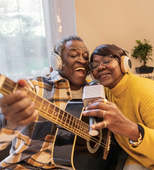 Man and woman with a guitar and microphone enjoying playing music