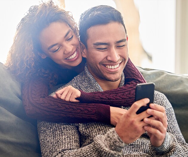 Happy couple looking at phone doing online shopping