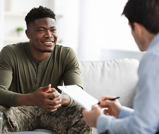 Young man sitting down and talking with a man holding a checklist