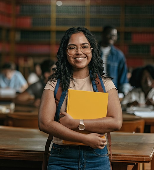 A young woman wearing a backpack and holding a textbook