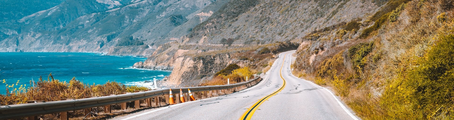 Curvy coastal road with ocean view against mountain backdrop in Central California