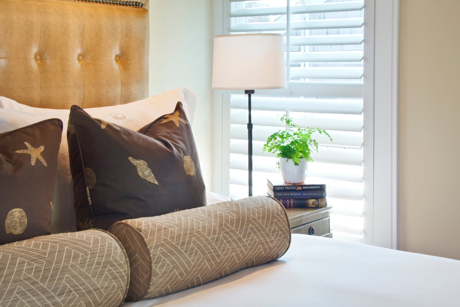 A bed with a tufted headboard and decorative pillows