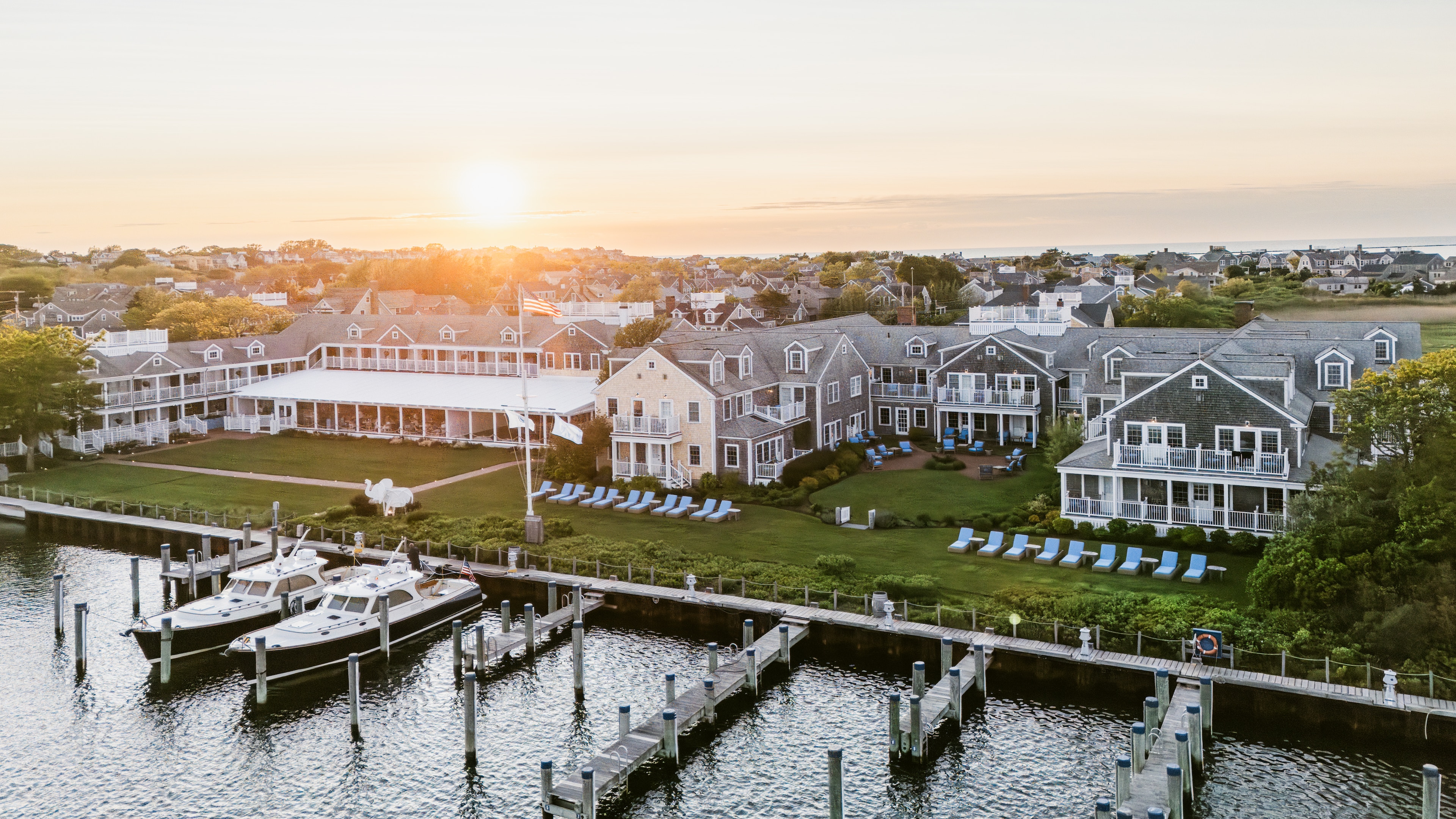 A waterfront hotel with a dock and boats at sunset.