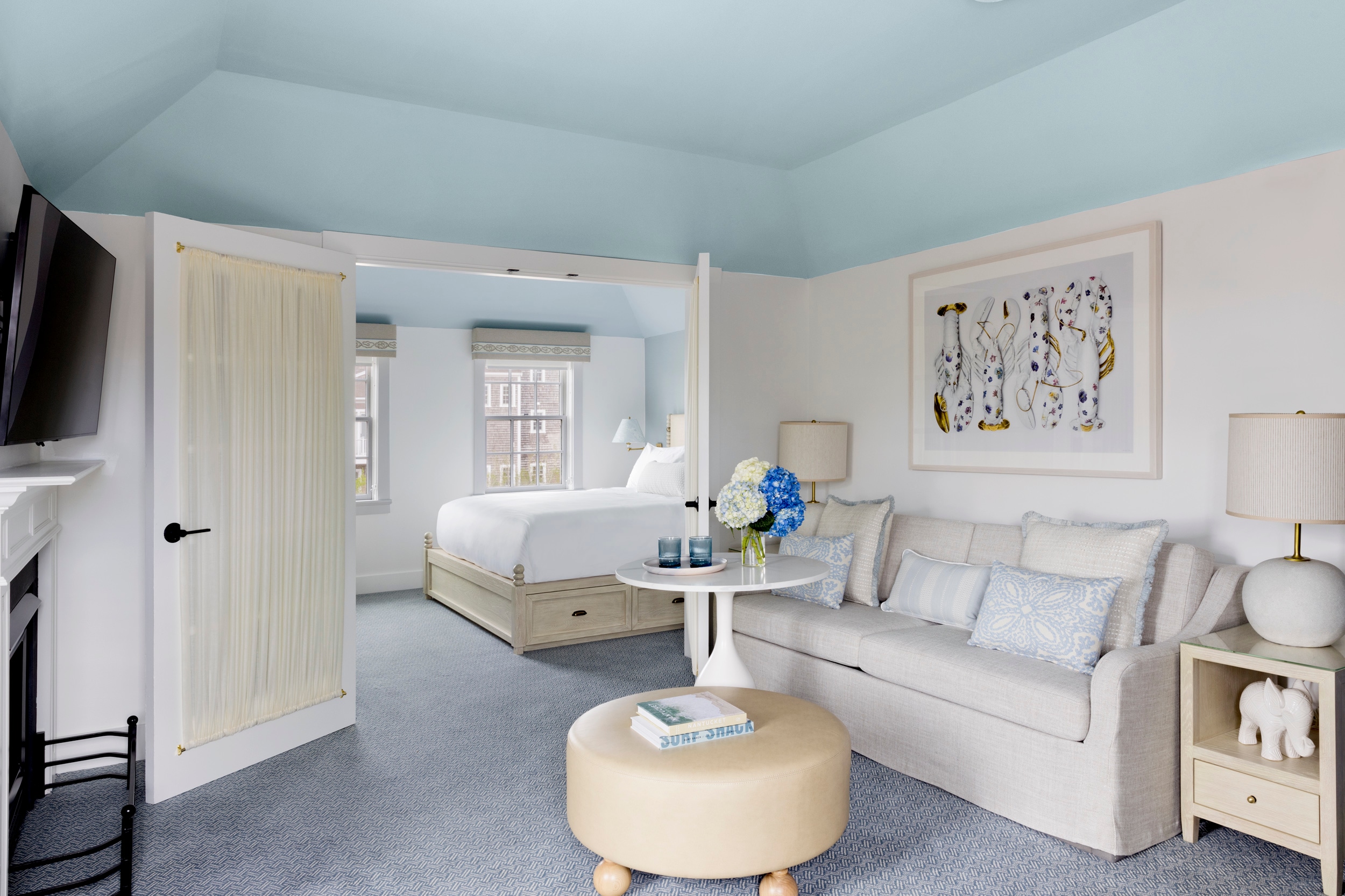 A wide view of a hotel room with a sofa, coffee table, bed, and artwork.