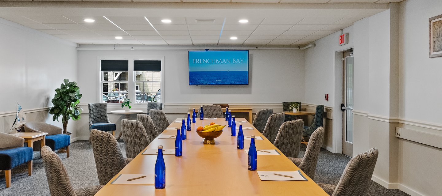 Long conference table with grey chairs, blue water bottles, notebooks