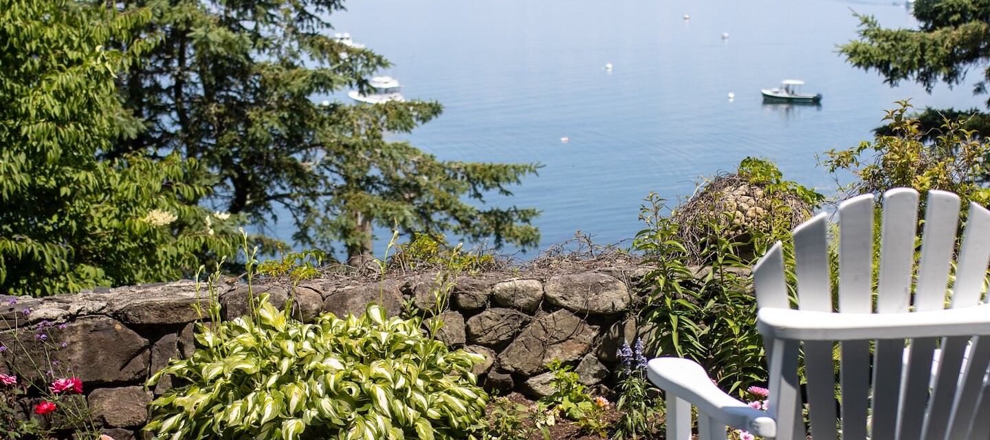 White Adirondack chair facing a serene lake with boats