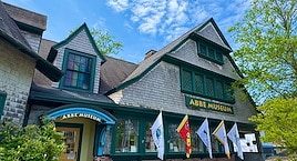 A woman in a blue jacket and floral scarf examines a display case in a museum