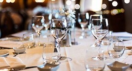 Elegant dining table set with wine glasses, plates, and folded napkins on a white tablecloth