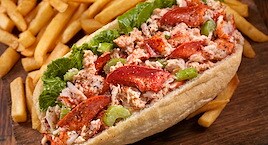 Lobster roll with lettuce, celery, and pepper on a soft bun
