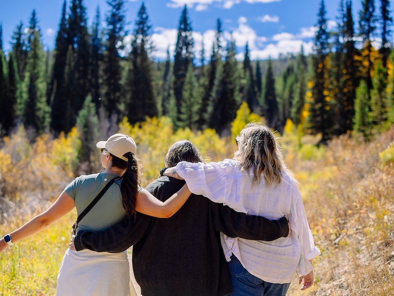 3 people standing on trail with arms around each other