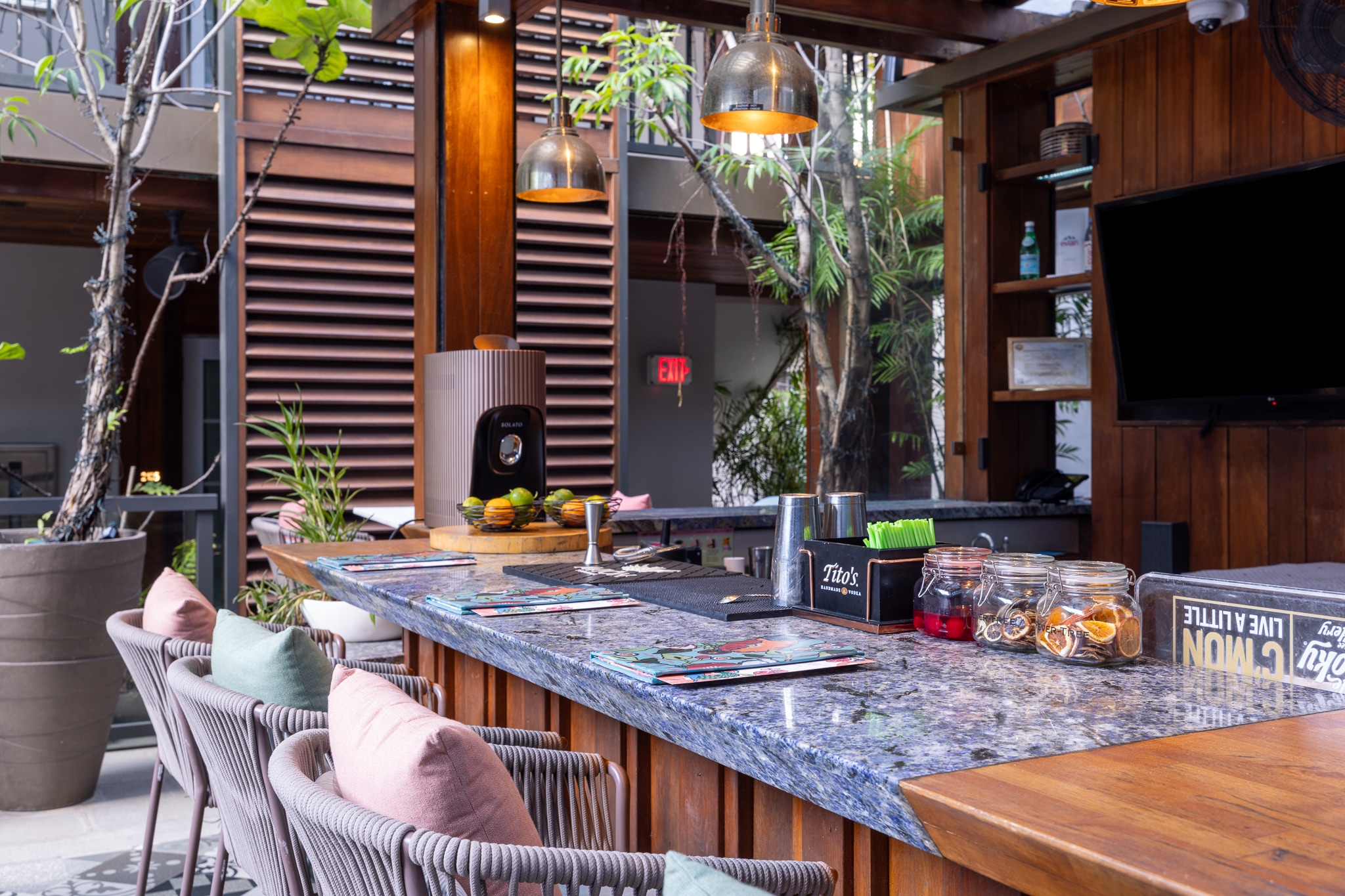 A bar with a granite countertop, bar stools, and a TV on the wall.