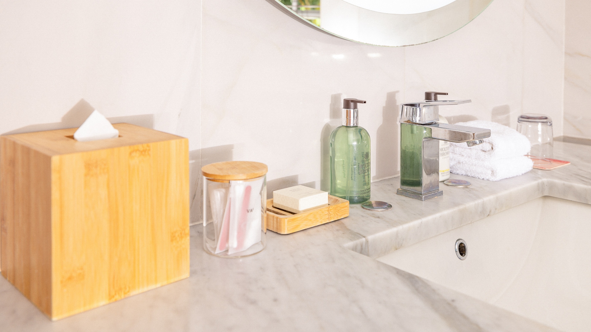 A bathroom counter with a marble countertop, a tissue box, a soap dispenser, and towels.