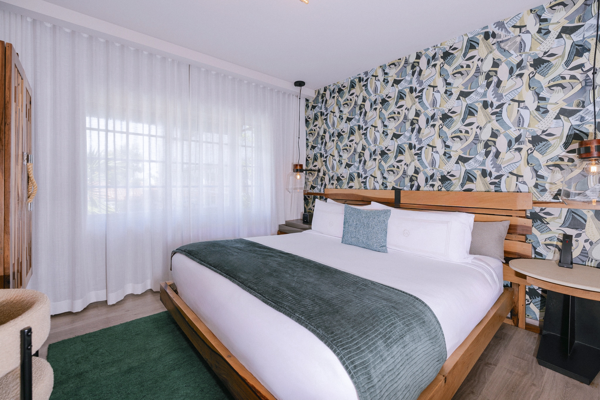 A hotel room with a large bed, wooden frame, and patterned wallpaper