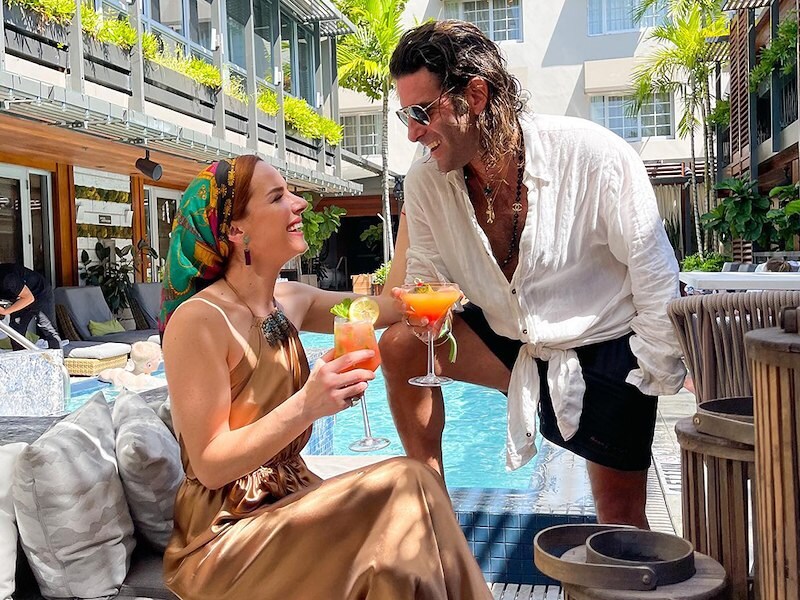 A man and woman enjoying drinks by the pool.