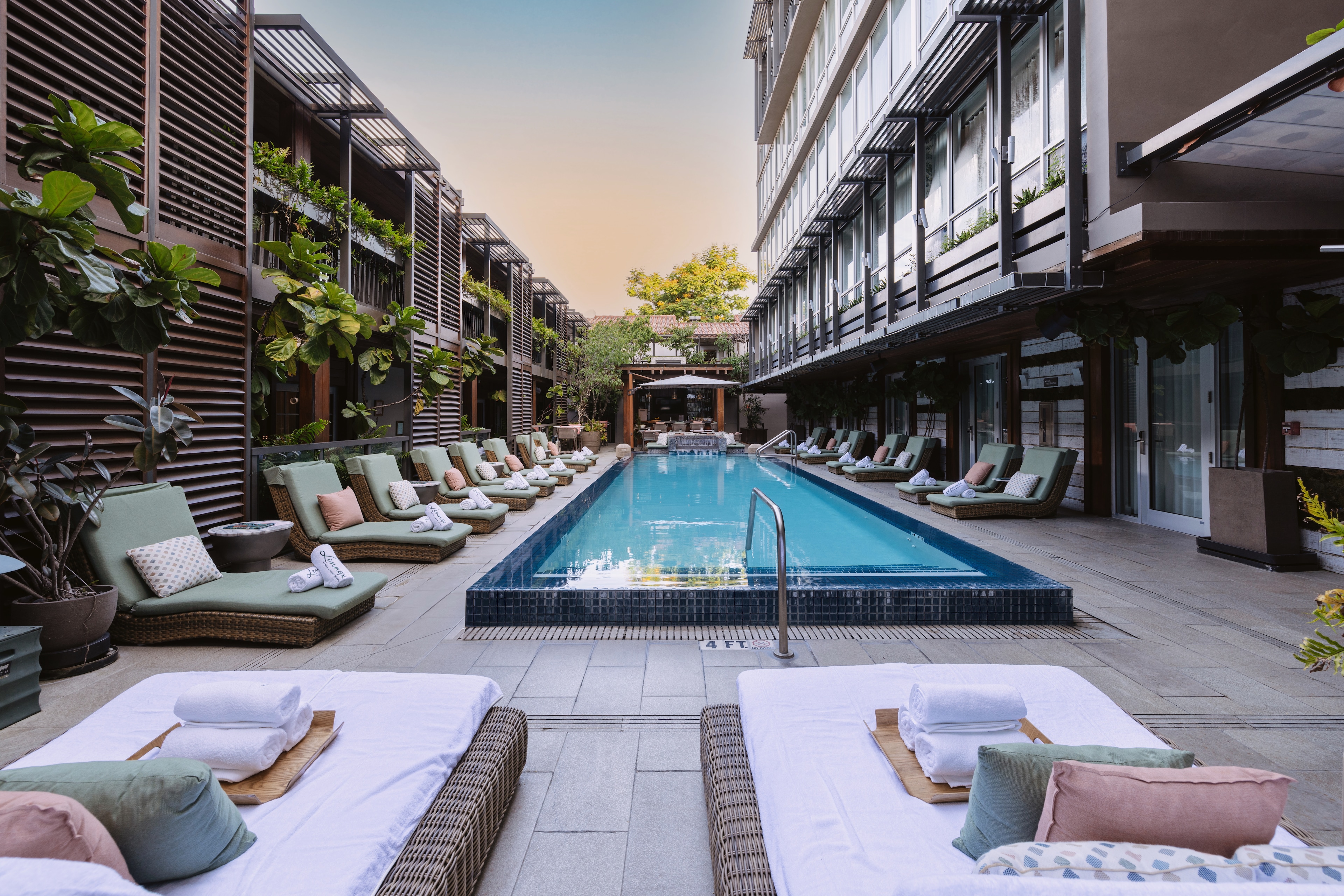 A swimming pool with lounge chairs and buildings in the background.