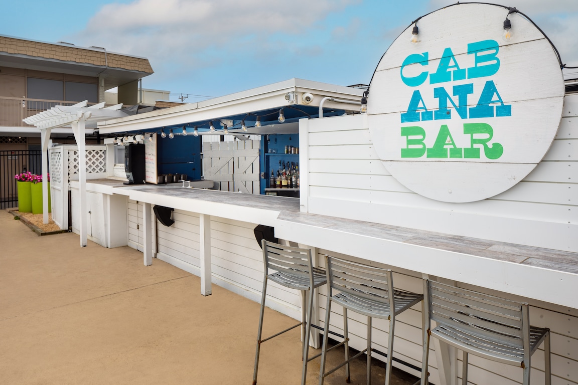 A white outdoor bar with a sign reading 'CABANA BAR' and outdoor seating.