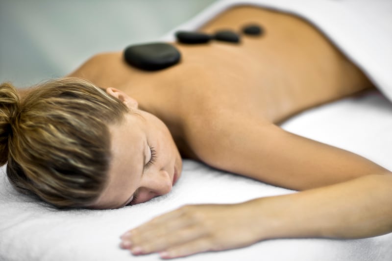 a woman lying on her stomach with stones on her back