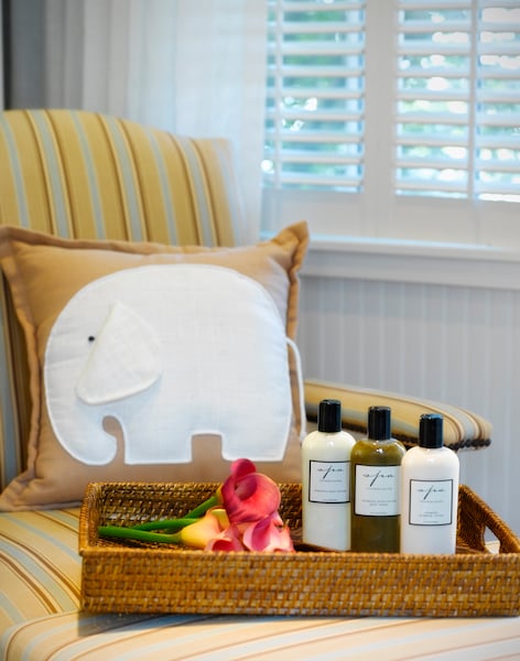 A wicker tray holding toiletries and flowers sits on a chair in a spa setting.