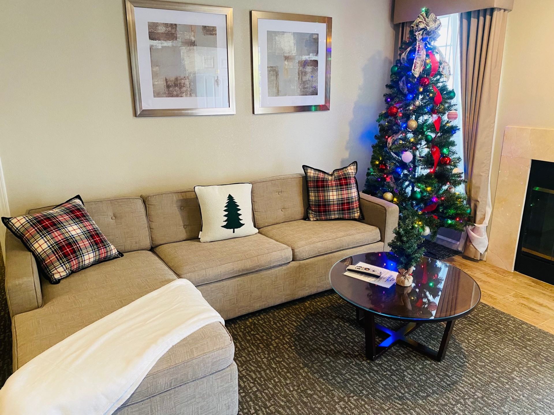 A cozy lobby with a Christmas tree, a couch, and a coffee table.